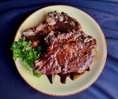 two pieces of steak on a plate with garnish