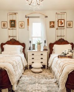 two twin beds in a bedroom with chandelier above them and pictures on the wall