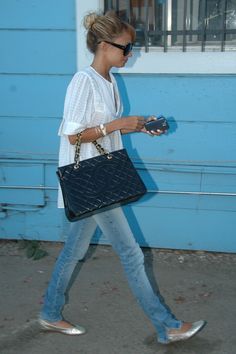 a woman walking down the street carrying a black purse