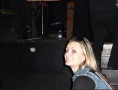 a woman sitting in front of a microphone on top of a wooden floor next to a stage