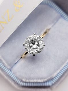 an engagement ring with a diamond in it's presentation box on top of a blue velvet case