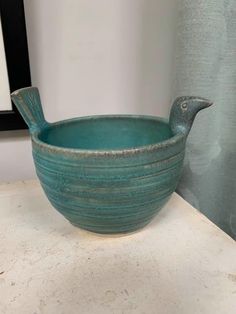 a blue bird shaped bowl sitting on top of a counter next to a framed photo