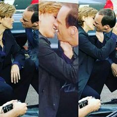 two men in suits kissing each other while sitting on the back of a car and another man standing behind them