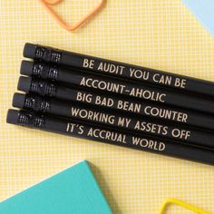 three black pencils with writing on them sitting next to some books and an eraser