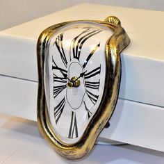 a white and gold clock sitting on top of a box