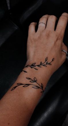 a woman's hand with a tattoo on her left wrist and an olive branch