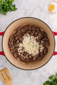 a pot filled with meat and onions sitting on top of a counter next to parsley