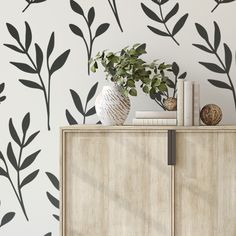 the wallpaper is decorated with black and white leaves, which are on top of a cabinet