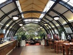 the inside of a restaurant with tables, chairs and bar stools in front of an arched ceiling