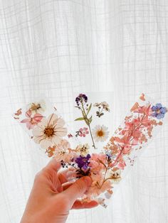 a person holding flowers in front of a white curtain