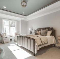 a bedroom with a large bed, two chairs and a lamp on the ceiling in front of a window