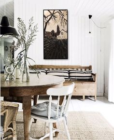 a dining room table with two chairs and a bench in front of the wall that has a painting on it