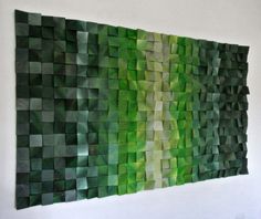 a painting made out of green squares on a white wall