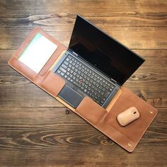 an open laptop computer sitting on top of a wooden table next to a mouse and keyboard