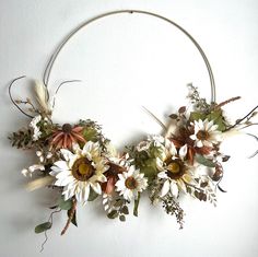 a circular wreath with flowers and leaves hanging on the wall