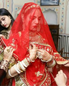 two women dressed in red and gold are getting ready to go on their wedding day