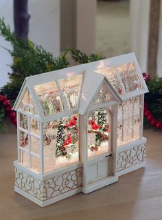 a small white house with christmas decorations on the windowsill and lights in front of it