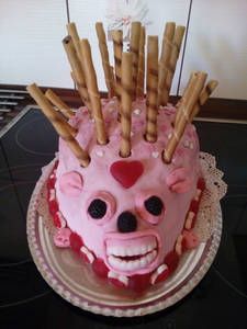 a pink cake with sticks sticking out of it's face on top of a table