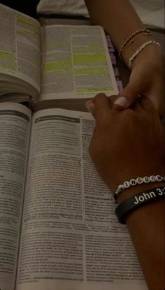 two people holding hands over an open book with the word john 3 16 written on it