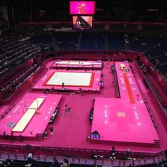 an empty tennis court is shown with pink tarps on the floor and people standing around it