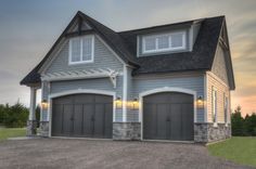 a large gray house with two garages on the front and one above it's doors