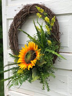 a wreath with sunflowers and greenery hangs on the side of a door