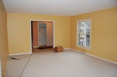 an empty room with yellow walls and white carpet, including a door to the closet