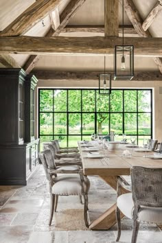 a large dining room table with chairs around it in front of an open window that looks out onto the woods