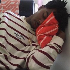 a young man sleeping on top of a couch wearing a red and white striped shirt