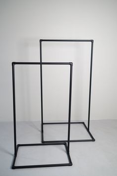 two black metal frames sitting next to each other on a white floor with no one in it