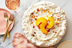 there is a pie with peaches on top and two forks next to it, along with pink plates