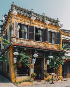 an old building with vines growing on the side and flowers hanging from it's windows