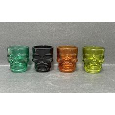 four different colored glass cups with skulls on the sides and one skull in the middle