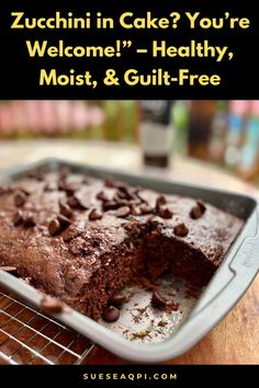 a chocolate cake sitting on top of a metal pan next to a cooling rack filled with cookies