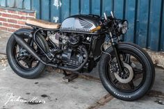 a black motorcycle parked next to a brick wall and blue door with writing on it