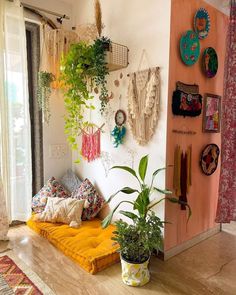 a living room filled with lots of plants and hanging decorations on the wall above it