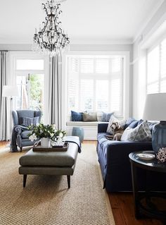 a living room filled with furniture and a chandelier hanging over the top of it