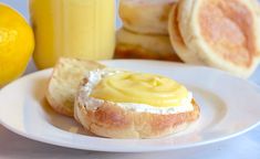 a plate topped with bread and butter next to two lemon juices on a table