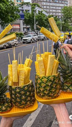 two trays filled with pineapple sticks sitting on top of a table next to a street