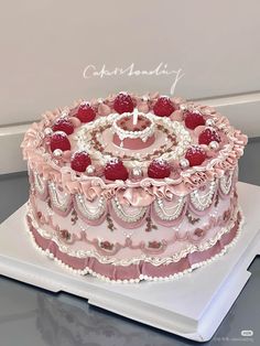 a pink and white cake with berries on top