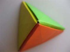 an orange, green and yellow origami piece sitting on top of a white surface