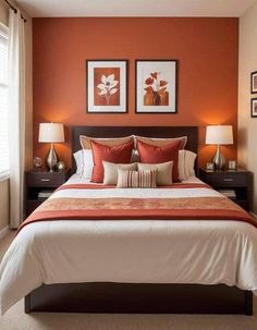 a bedroom with orange walls and white bedding, two framed pictures on the wall