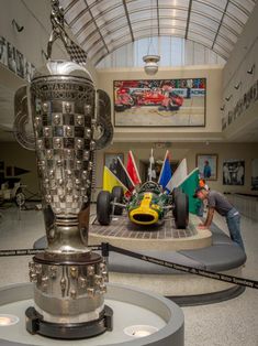 a man laying on the ground next to a trophy in a building with people looking at it