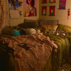 a bed with blankets and stuffed animals on it in a room filled with pictures hanging on the wall