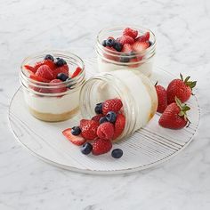 three jars filled with fruit sitting on top of a white plate next to each other