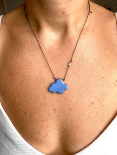 a woman wearing a necklace with a blue cloud on it