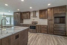 a large kitchen with wooden cabinets and marble counter tops, along with stainless steel appliances