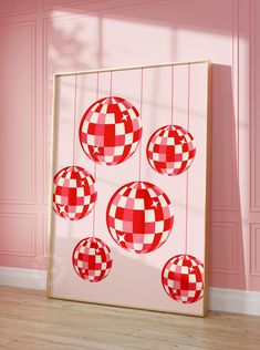 red and white checkered ornaments hanging on a pink wall in a room with wood flooring