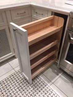 an open cabinet in the middle of a kitchen countertop with white tile flooring