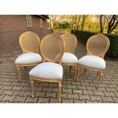 four wicker dining chairs with white cushions